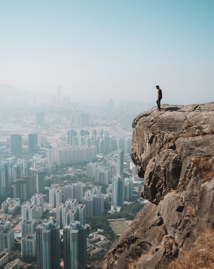 A man standing on the top of a mountain and watching a big city